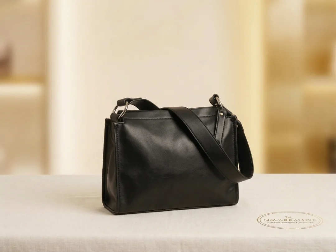 Smooth black leather crossbody bag with clean lines and an adjustable strap.