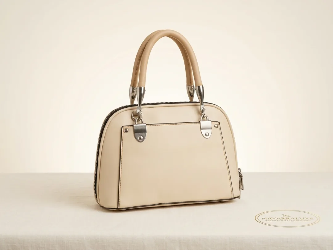 Cream structured dome satchel with rolled top handles and polished silver hardware.